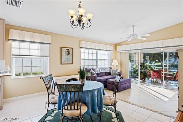 dining room featuring light tile patterned floors, visible vents, vaulted ceiling, baseboards, and ceiling fan with notable chandelier