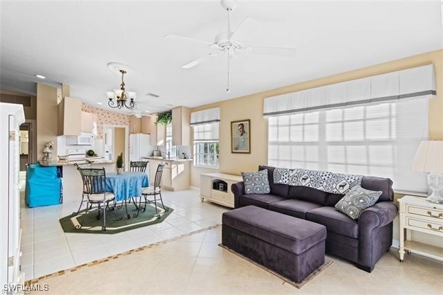 living room featuring light tile patterned flooring and ceiling fan with notable chandelier