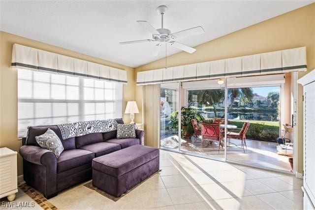 living room featuring lofted ceiling, light tile patterned floors, and a ceiling fan