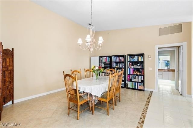 dining space featuring light tile patterned flooring, an inviting chandelier, visible vents, and baseboards