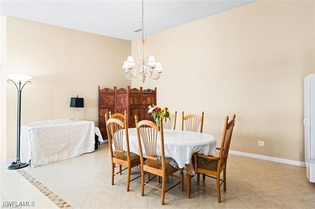 dining area with light tile patterned flooring, baseboards, and an inviting chandelier