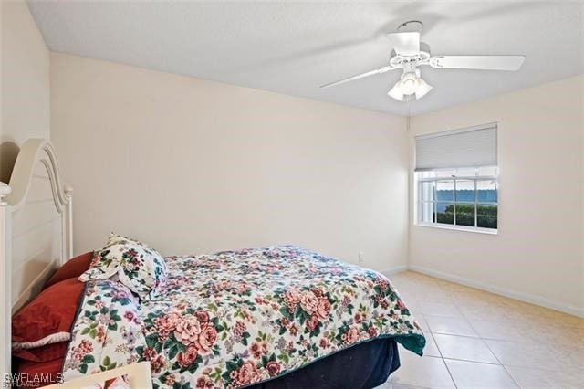 tiled bedroom featuring baseboards and a ceiling fan