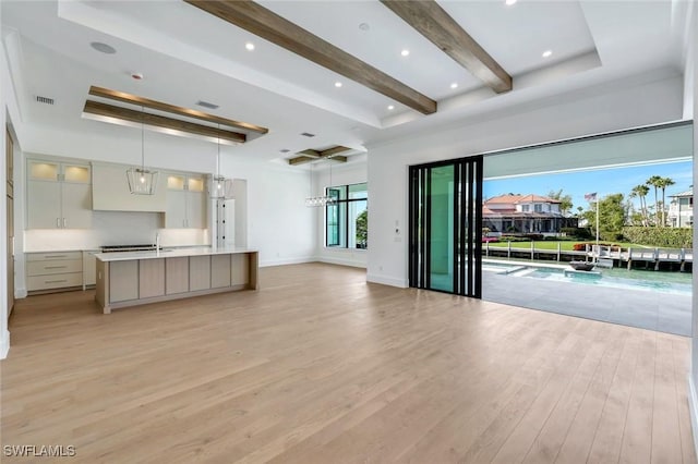 unfurnished living room featuring visible vents, light wood-type flooring, beam ceiling, and baseboards