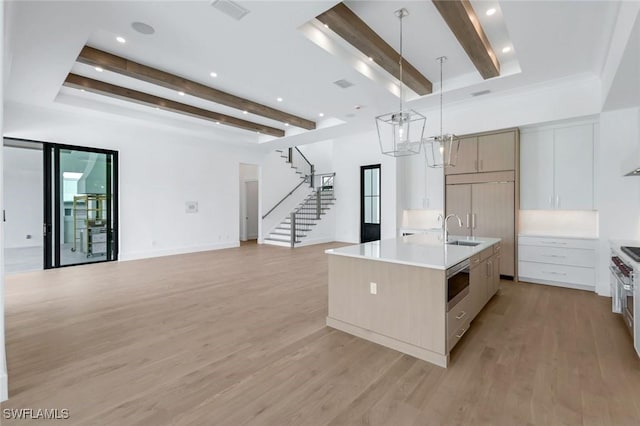 kitchen with white cabinets, open floor plan, light countertops, an island with sink, and decorative light fixtures