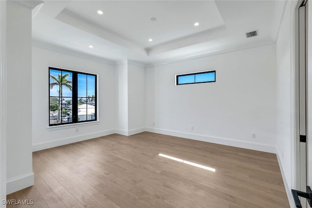 unfurnished room featuring light wood-type flooring, a raised ceiling, visible vents, and baseboards