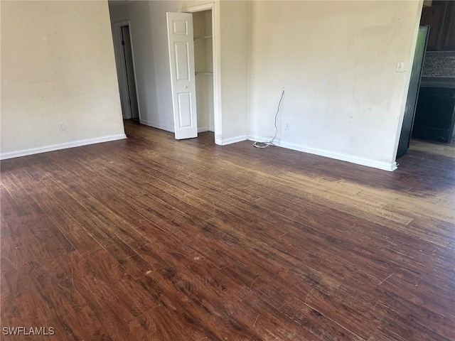 spare room featuring dark wood-style floors and baseboards