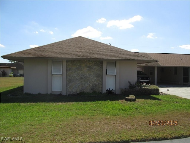 view of side of home with concrete driveway, an attached carport, a lawn, and a shingled roof