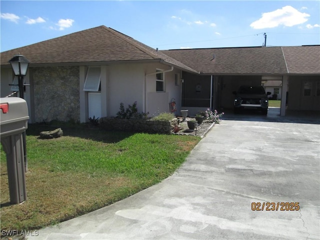 ranch-style house featuring driveway, roof with shingles, a front yard, a carport, and stucco siding