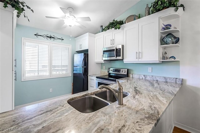 kitchen featuring light stone countertops, stainless steel appliances, white cabinetry, open shelves, and a sink