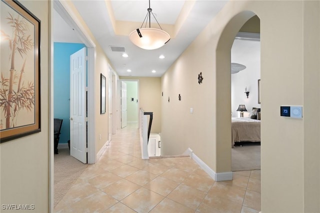 corridor featuring arched walkways, recessed lighting, visible vents, light tile patterned flooring, and baseboards