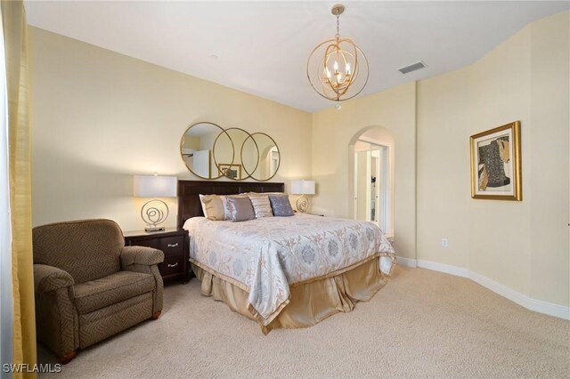 carpeted bedroom featuring baseboards, visible vents, arched walkways, and a chandelier