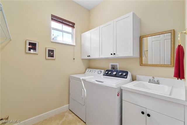 washroom with light tile patterned floors, separate washer and dryer, a sink, baseboards, and cabinet space