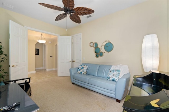 living room with ceiling fan, arched walkways, carpet flooring, visible vents, and baseboards