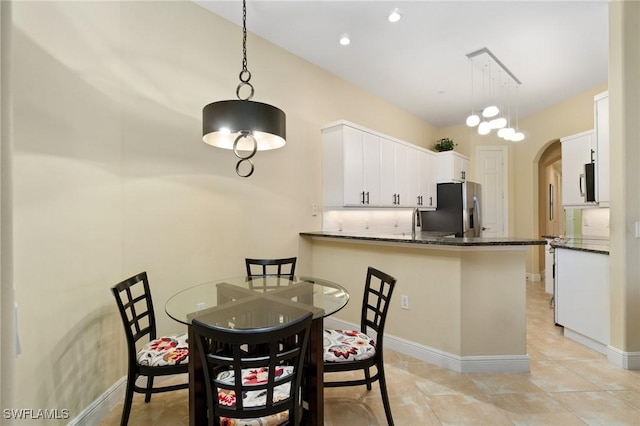 dining room featuring arched walkways, recessed lighting, light tile patterned flooring, and baseboards