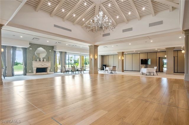 unfurnished living room with visible vents, light wood-type flooring, a fireplace, and decorative columns