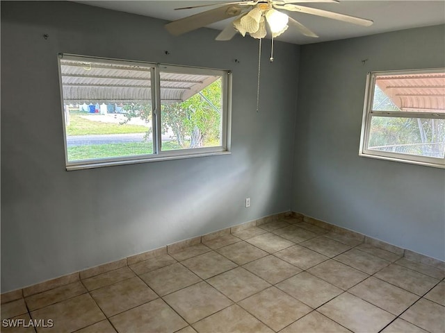 empty room featuring plenty of natural light, ceiling fan, and light tile patterned flooring