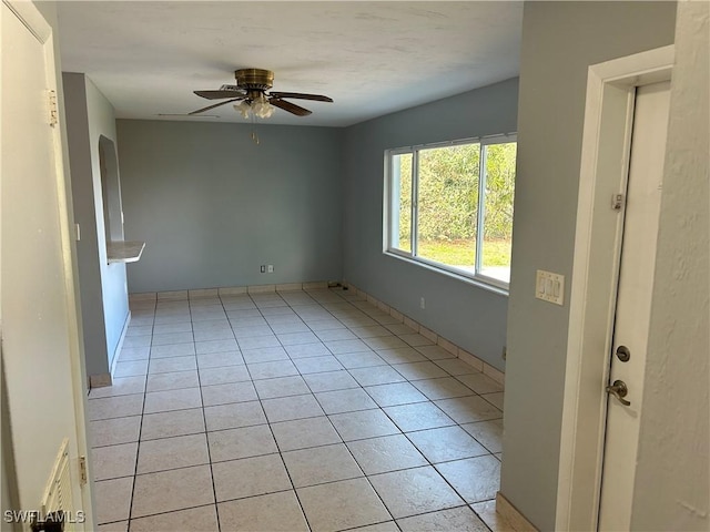 empty room with ceiling fan and light tile patterned flooring