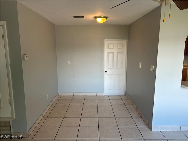 unfurnished room featuring light tile patterned floors, baseboards, visible vents, and a ceiling fan