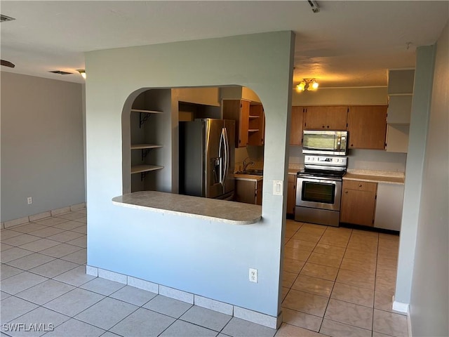 kitchen with built in shelves, light tile patterned floors, stainless steel appliances, light countertops, and brown cabinetry