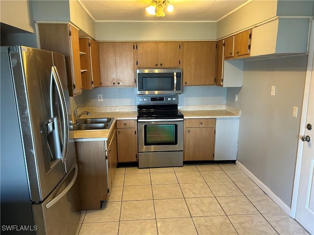 kitchen featuring light tile patterned floors, appliances with stainless steel finishes, brown cabinets, light countertops, and a sink