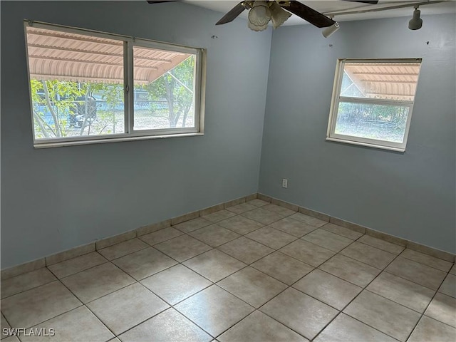 spare room featuring ceiling fan, light tile patterned flooring, and baseboards