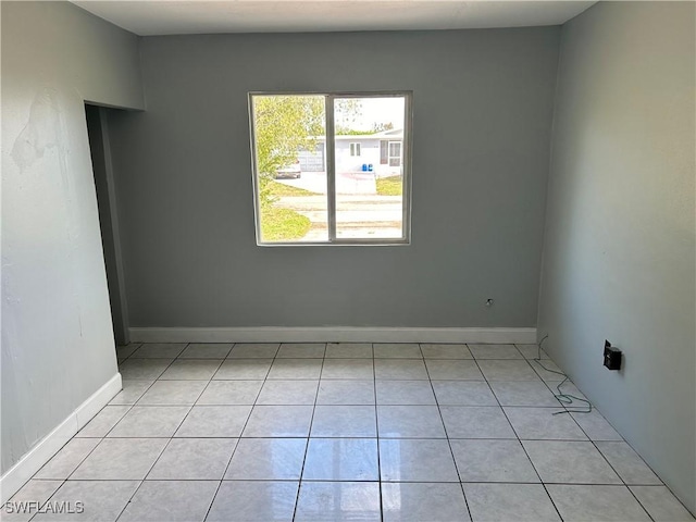 spare room featuring light tile patterned floors and baseboards