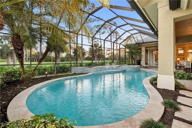 view of swimming pool featuring a pool with connected hot tub, glass enclosure, a patio, and ceiling fan