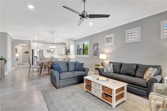 living area with baseboards, arched walkways, crown molding, and recessed lighting