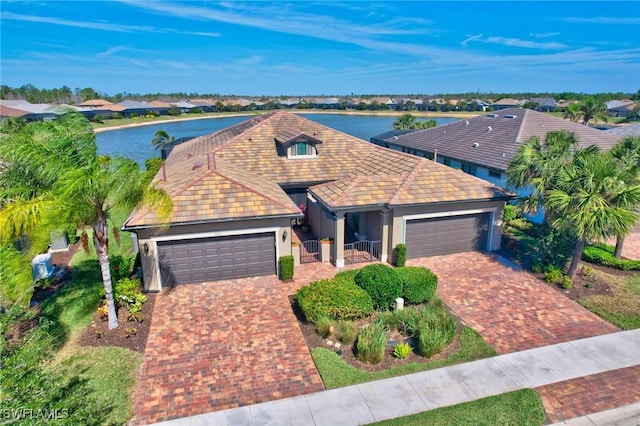 view of front of house with a water view, a garage, decorative driveway, and a tiled roof