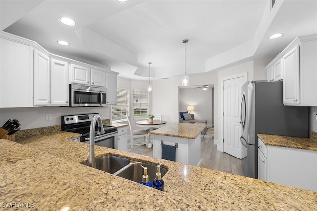 kitchen featuring white cabinetry, stainless steel appliances, light stone counters, and a raised ceiling