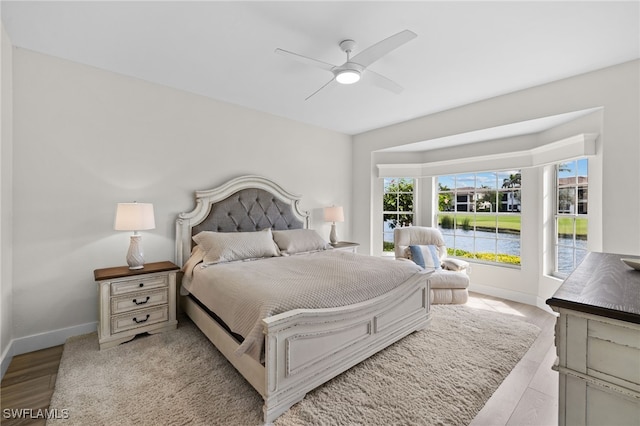 bedroom featuring light wood-type flooring, baseboards, and a ceiling fan