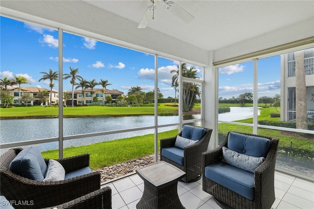 sunroom with a ceiling fan and a water view