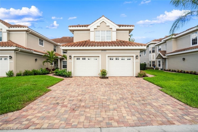 mediterranean / spanish house with decorative driveway, stucco siding, an attached garage, a front yard, and a tiled roof