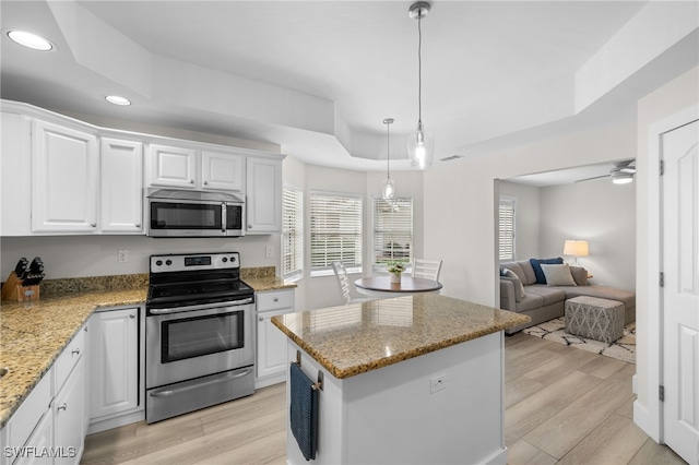 kitchen with recessed lighting, a raised ceiling, light wood-style flooring, appliances with stainless steel finishes, and white cabinetry