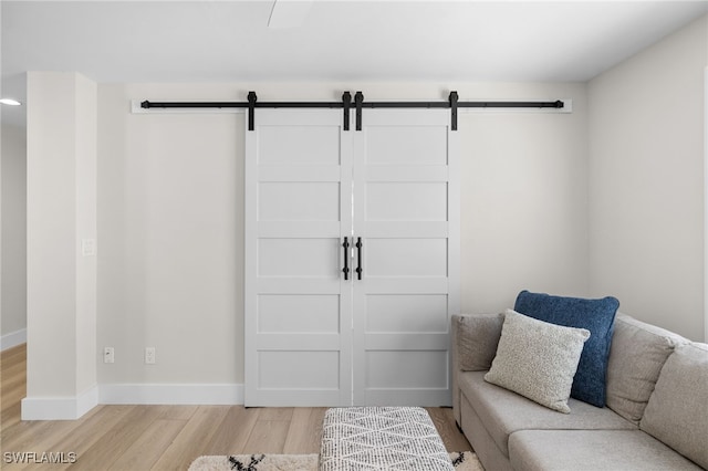 living area with light wood-style floors, a barn door, and baseboards