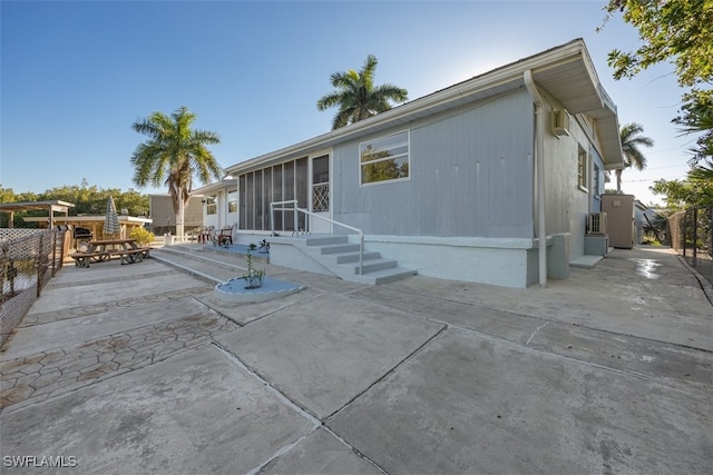 back of house with entry steps, a sunroom, and a patio area