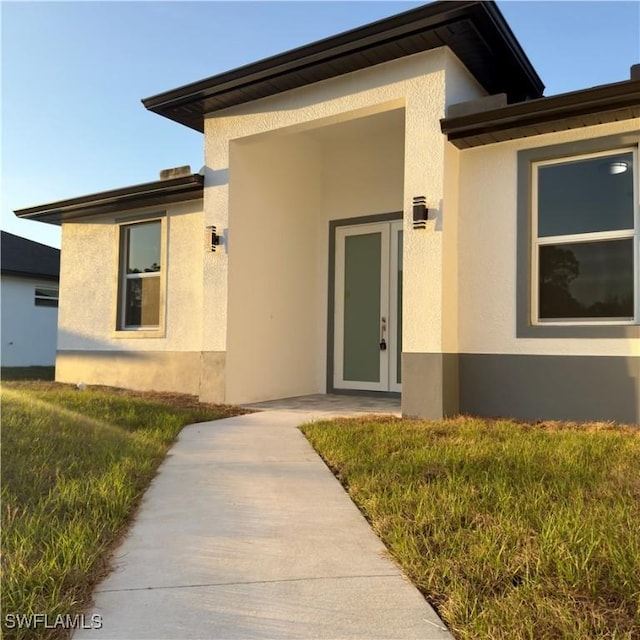 entrance to property with a yard and stucco siding