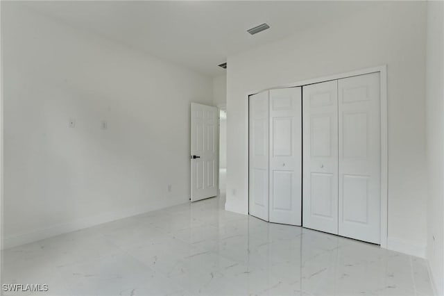 unfurnished bedroom featuring marble finish floor, visible vents, baseboards, and a closet