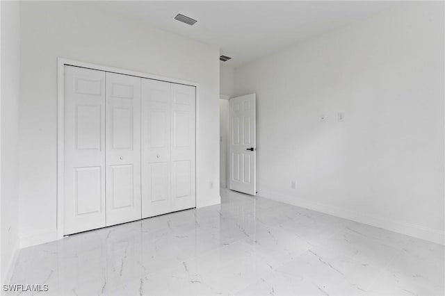 unfurnished bedroom featuring marble finish floor, a closet, visible vents, and baseboards