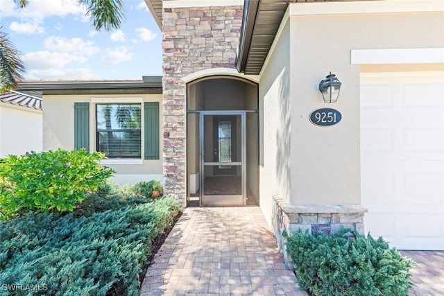 property entrance featuring stone siding, an attached garage, and stucco siding