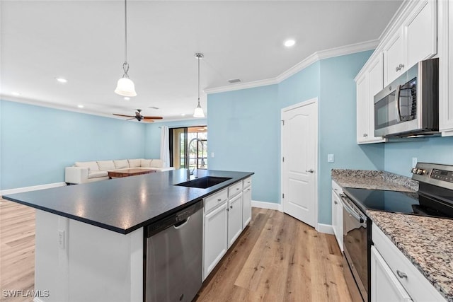 kitchen featuring a sink, ornamental molding, appliances with stainless steel finishes, light wood finished floors, and an island with sink