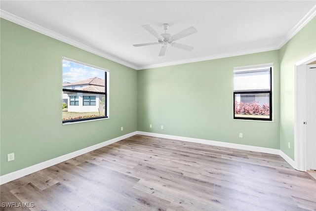 empty room with baseboards, wood finished floors, a wealth of natural light, and crown molding