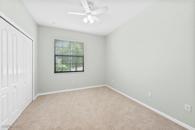 unfurnished bedroom featuring ceiling fan, a closet, carpet flooring, and baseboards