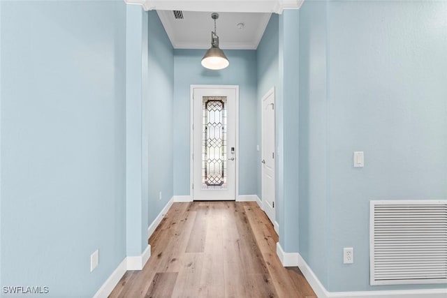 entryway with visible vents, crown molding, baseboards, and wood finished floors