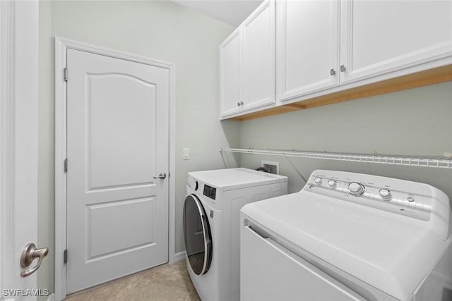 laundry area featuring light tile patterned floors, washer and clothes dryer, and cabinet space