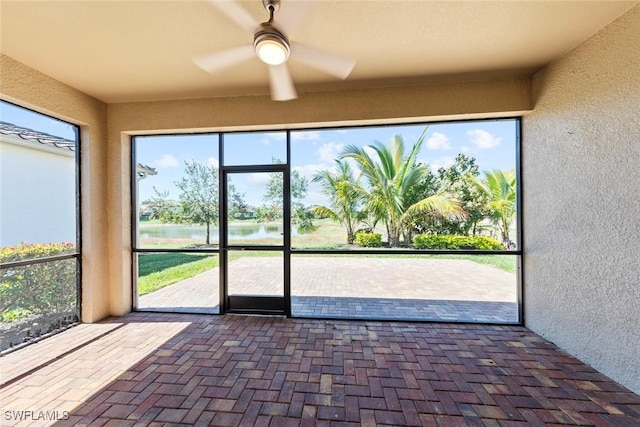 unfurnished sunroom with a water view and ceiling fan