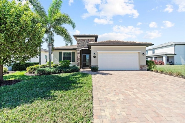 view of front of house featuring decorative driveway, a front yard, stone siding, and an attached garage