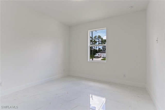 empty room featuring marble finish floor and baseboards