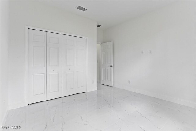 unfurnished bedroom with marble finish floor, baseboards, visible vents, and a closet