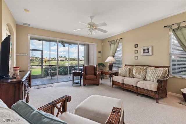 carpeted living room with a healthy amount of sunlight, ceiling fan, visible vents, and baseboards